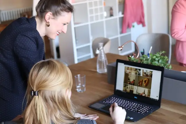 dos mujeres en una oficina viendo una laptop