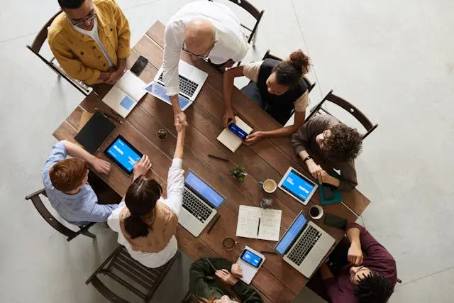 varias personas en mesa de trabajo con laptops