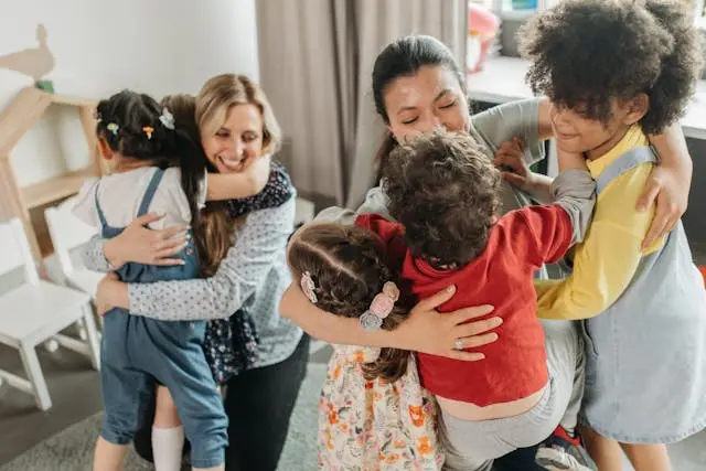 varios niños abrazando a sus maestros